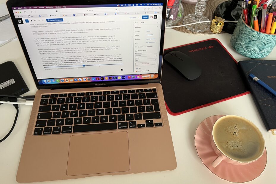 Atvērts klēpjdators ar kafijas krūzi blakām